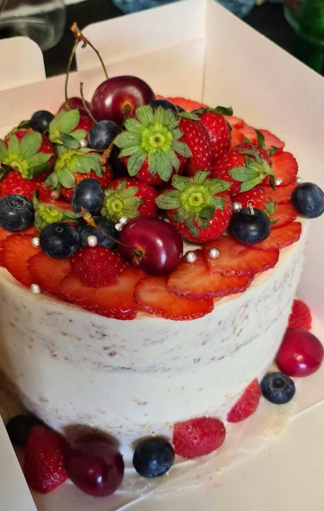 A request for a birthday cake featuring fruit. This ones a vanilla cake with homemade strawberry jam and buttercream. Its decorated semi-naked and topped with fruits, strawberry 🍓, cherry  🍒 and blueberries