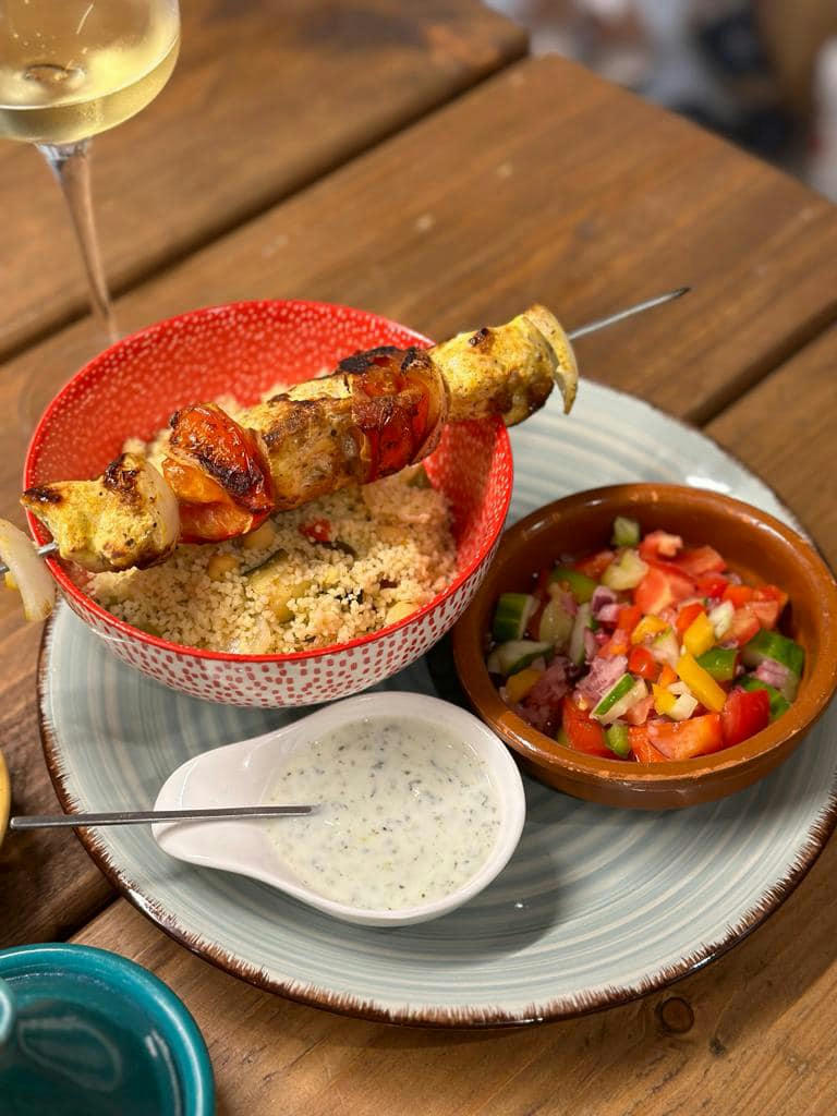 Chicken skewer infused with Morrocan spices (purchased from Marrakesh), Couscous bejeweled with roasted vegetables (peppers, aubergine, courgette, onions) and chickpeas with a typical colourful Moroccan salad on the side and a jogurt and mint dressing for dipping. - September 2023