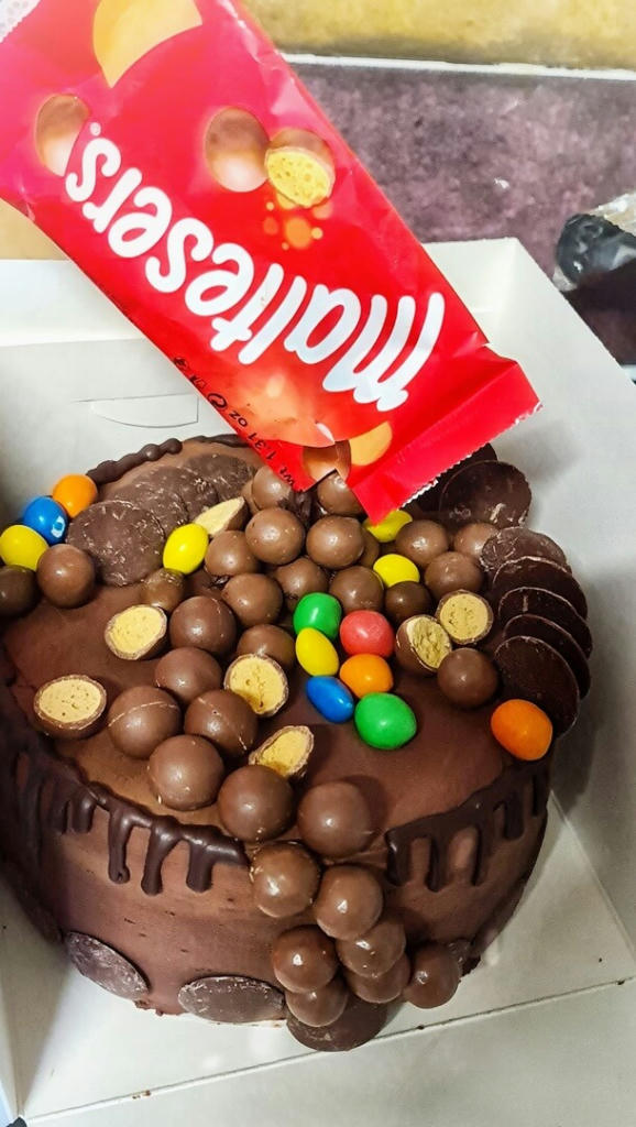 A gooey chocolate fudge cake, filled with chocolate nut ganache, covered with chocolate ganache. Its decorated with all things chocolate maltesers, M&Ms, Aero, giant chocolate buttons and a chocolate drip.