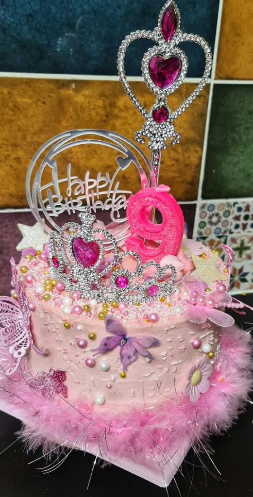 3 layers of different pink vanilla sponge filled with homemade strawberry jam and vanilla buttercream. Coated with pink buttercream dusted with edible glitter. The decorations included edible lace butterflies, meringue kisses (all sparkling) princess sprinkles, white chocolate stars.